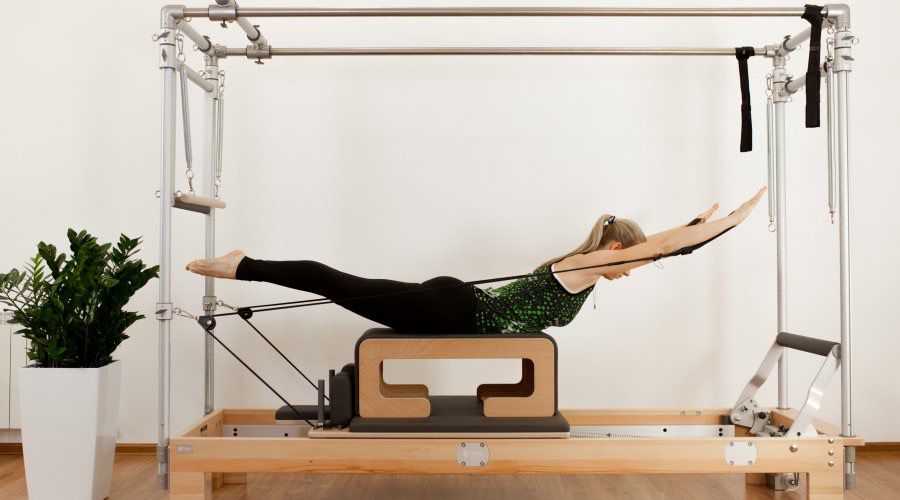 mujer estirando pierna con máquina de pilates