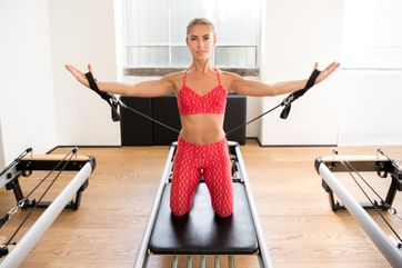 mujer de rojo realizando estiramientos con brazos extendidos