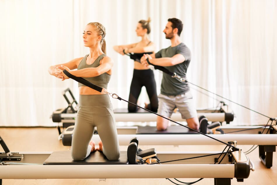 grupo haciendo pilates en cama reformer